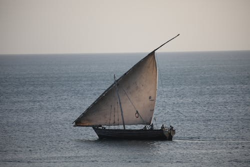 Classic dhow with lateen sail on calm turquoise water